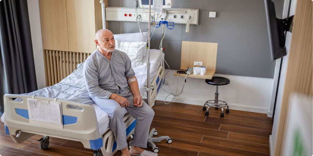 Man sitting on the side of the bed in a hospital